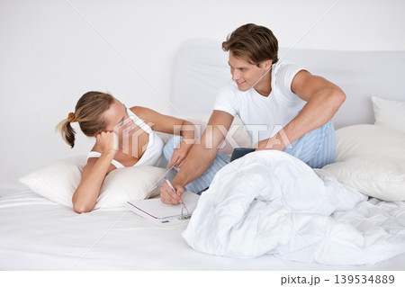 Happy couple, writing and morning in bed for budget planning, documents or notes at home. Man and woman smile or lying with notebook or calculator in bedroom finance or financial checklist at house 139534889