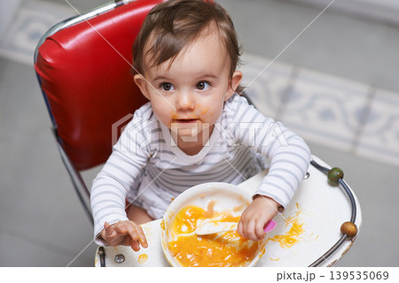 Child eating, high chair and food, nutrition and health for childhood development and wellness. Healthy, growth and toddler person at home, vegetable or fruit, hungry baby with lunch or dinner meal 139535069