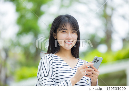屋外でスマホを操作する若い女性 139535090