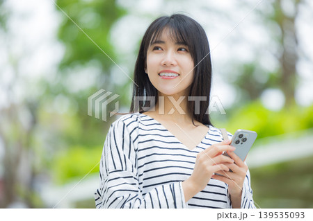 屋外でスマホを操作する若い女性 屋外でスマホを操作する若い女性 139535093
