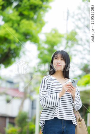 屋外でスマホを操作する若い女性 139535098