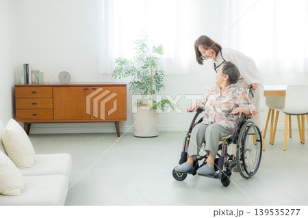 車椅子のシニア女性と介護するミドル女性 車椅子のシニア女性と介護するミドル女性 139535277