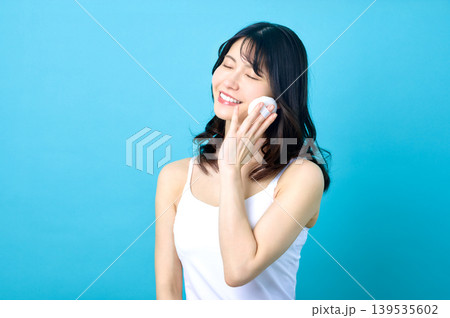 目を閉じて満面の笑顔でパフを頬に当てる若い日本人女性 目を閉じて満面の笑顔でパフを頬に当てる若い日本人女性 139535602