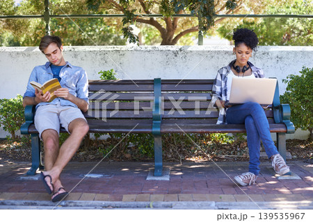 College, campus and students in the park study on a bench with laptop, book and reading. University, academy and people sitting outdoor learning with research, project and knowledge for education 139535967