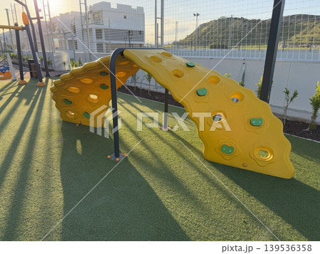 Colorful climbing playground equipment outdoors with sunlight casting shadows in the afternoon Colorful climbing playground equipment outdoors with sunlight casting shadows in the afternoon 139536358