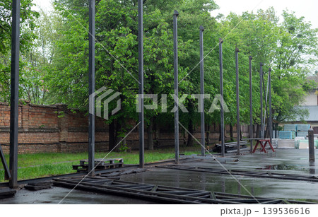 Row of vertical steel pillars at an outdoor construction site for a new industrial building or warehouse frame. Row of vertical steel pillars at an outdoor construction site for a new industrial building or warehouse frame. 139536616