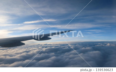 horizontal photo of close up airplane wing extending over thick cloud layer with clear blue sky and sunlight streaks above with copy space horizontal photo of close up airplane wing extending over thick cloud layer with clear blue sky and sunlight streaks above with copy space 139536623