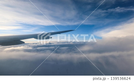 horizontal photo of close up airplane wing extending over thick cloud layer with clear blue sky and sunlight streaks above with copy space horizontal photo of close up airplane wing extending over thick cloud layer with clear blue sky and sunlight streaks above with copy space 139536624