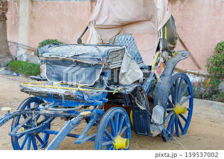 Dilapidated blue horse-drawn carriage on sandy ground Dilapidated blue horse-drawn carriage on sandy ground 139537002