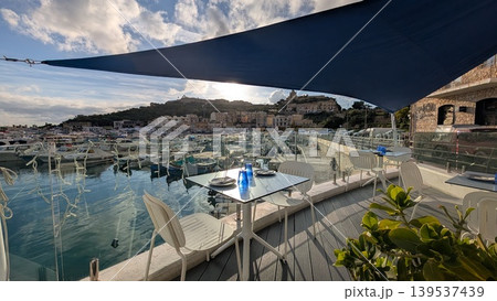 View of a luxury resort with boats and yachts in the harbor under blue awnings View of a luxury resort with boats and yachts in the harbor under blue awnings 139537439