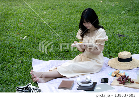 beautiful young woman smiling while sitting in a meadow enjoying write note beautiful young woman smiling while sitting in a meadow enjoying write note 139537603