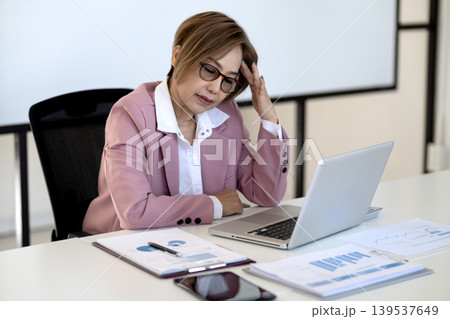 Senior businesswoman is stressed and thinking while working Senior businesswoman is stressed and thinking while working 139537649