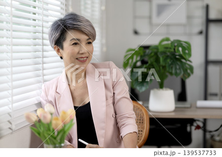 Senior businesswoman relaxing at desk in office while taking a break from work 139537733