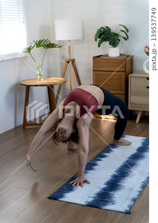 A fifty year old + woman doing yoga poses with her back stretched and her hands A fifty year old + woman doing yoga poses with her back stretched and her hands 139537749