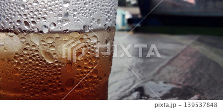 Close up of cold iced tea with water spray in a plastic cup. Close up of cold iced tea with water spray in a plastic cup. 139537848