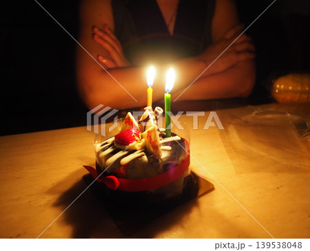Birthday cake candle celebration dessert flame party chocolate cake warm dim light with person arms crossed near festive table Birthday cake candle celebration dessert flame party chocolate cake warm dim light with person arms crossed near festive table 139538048
