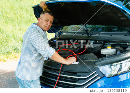 Driver connecting jumper cables to truck battery Driver connecting jumper cables to truck battery 139538119