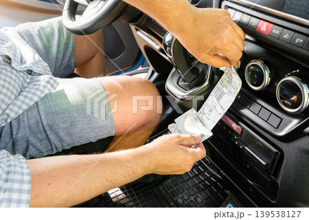 Driver holding long tachograph paper in truck cab 139538127