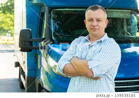 Confident truck driver with arms crossed near van Confident truck driver with arms crossed near van 139538185
