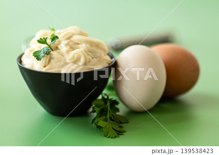 creamy mayonnaise sauce in bowl on green background 139538423
