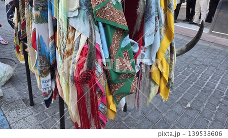 Colorful hanging scarves and traditional shawls displayed on stand with fringes and patterned fabrics for la vaquilla colmenar viejo festival market background Colorful hanging scarves and traditional shawls displayed on stand with fringes and patterned fabrics for la vaquilla colmenar viejo festival market background 139538606