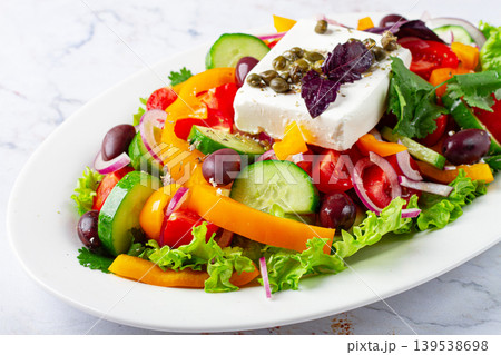 Greek salad, with vegetables and feta cheese, served on a white plate, no people. 139538698