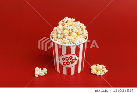 Popcorn in striped bucket on red background with copy space. Cinema promotion concept. 139538814