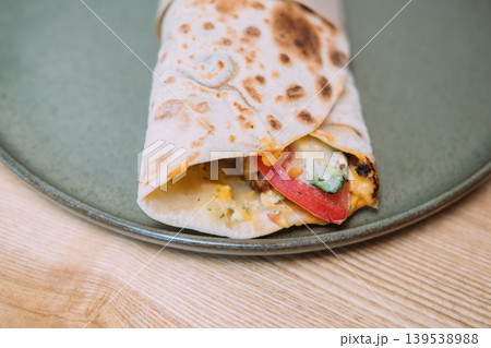 Doner kebab. Street food. Grilled shawarma wrapped in flatbread served on plate. Tasty fast meal production with tomato cucumber sauce. Doner kebab. Street food. Grilled shawarma wrapped in flatbread served on plate. Tasty fast meal production with tomato cucumber sauce. 139538988