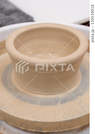 Ceramic artisan. Pottery art. Raw clay pot on spinning electric wheel professional equipment for handmade craft in workspace. Ceramic artisan. Pottery art. Raw clay pot on spinning electric wheel professional equipment for handmade craft in workspace. 139539018