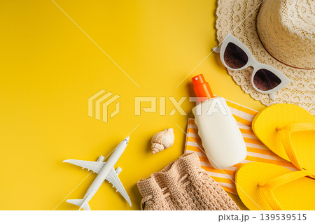 Summer holiday flat lay yellow background. Beach travel accessories for vacation. Airplane, sunglasses, sun hat, sunscreen. Copy space 139539515
