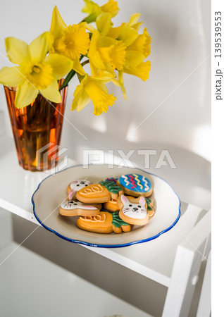 Easter spring background. Easter cookies with colourful icing: bunnies, carrots and eggs in a plate with bouquet of fresh. Bright and airy photo Easter spring background. Easter cookies with colourful icing: bunnies, carrots and eggs in a plate with bouquet of fresh. Bright and airy photo 139539553