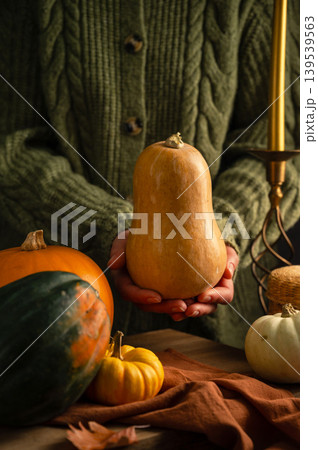 Orange, green and white squashes, female hands holding pumpkin, rustic wooden moody background, autumn concept 139539563