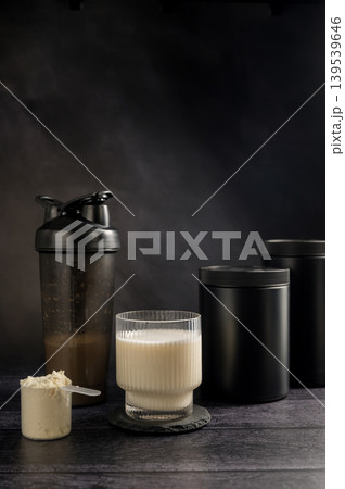 Protein drink in a glass with protein shaker and tube on dark background. Body building, muscle growth and food supplement concept 139539646
