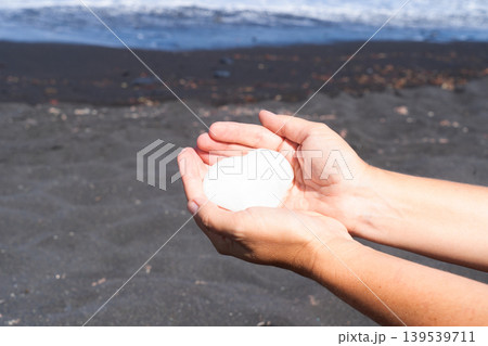 woman meditating on beach shore and holding crystal heart 139539711