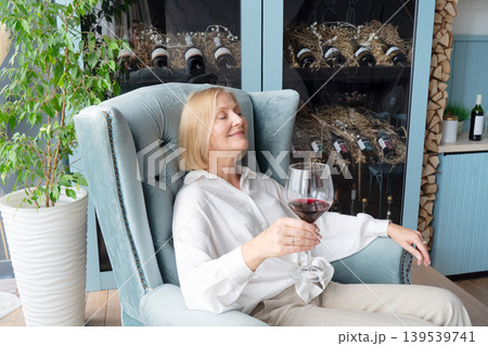 An Elegant Woman Joyfully Toasting with a Glass of Rich Red Wine in a Beautifully Stylish Kitchen Space 139539741