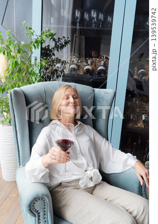 An Elegant Woman Joyfully Toasting with a Glass of Rich Red Wine in a Beautifully Stylish Kitchen Space An Elegant Woman Joyfully Toasting with a Glass of Rich Red Wine in a Beautifully Stylish Kitchen Space 139539742