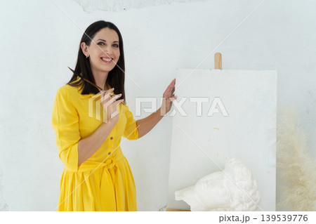 A Joyful Artist Proudly Showcasing Their Colorful Paint Brushes in a Bright and Inspiring Studio Environment 139539776