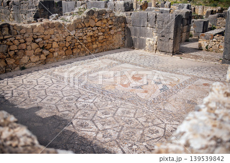 Ancient mosaic floor with intricate geometric patterns and vibrant colors, surrounded by stone ruins, showcasing historical craftsmanship and archaeological significance Ancient mosaic floor with intricate geometric patterns and vibrant colors, surrounded by stone ruins, showcasing historical craftsmanship and archaeological significance 139539842