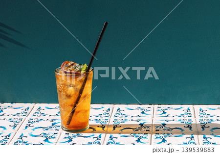 A cool cup of fruit soda with ice cubes on the table with patterned tiles 139539883