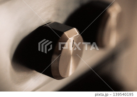 Close-up view of stainless steel control knobs on a kitchen appliance, featuring a sleek design and modern aesthetic, highlighting the texture and finish of the materials Close-up view of stainless steel control knobs on a kitchen appliance, featuring a sleek design and modern aesthetic, highlighting the texture and finish of the materials 139540195