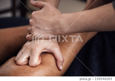 Professional massage therapist applying deep tissue technique on a client's leg, showcasing relaxation and wellness in a serene spa environment with soft lighting Professional massage therapist applying deep tissue technique on a client's leg, showcasing relaxation and wellness in a serene spa environment with soft lighting 139540265