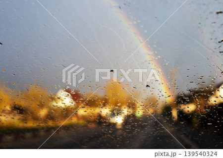 Colorful rainbow through wet glass. Stormy scene with reflections and colorful skies Colorful rainbow through wet glass. Stormy scene with reflections and colorful skies 139540324
