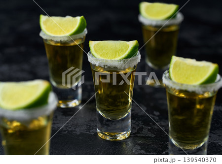 Tequila shot with lime slices . Mexican tequila on a dark table, selective focus. 139540370
