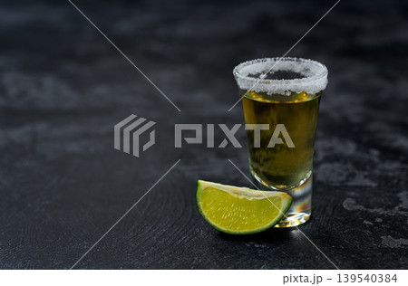 golden tequila with white salt crystals and lime on a dark table,  selective focus. 139540384
