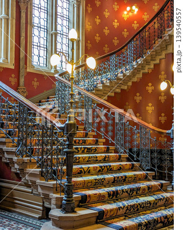Ornate Historic Staircase Interior with Decorative Iron Railings Patterned Carpet Ornate Historic Staircase Interior with Decorative Iron Railings Patterned Carpet 139540557