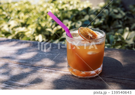 Close-up of a delicious citrus cocktail in a glass on a wooden round table Close-up of a delicious citrus cocktail in a glass on a wooden round table 139540643
