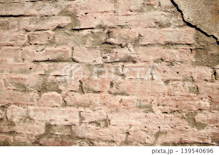 Old pink textured crumbling wall made of bricks plastered with brown clay Old pink textured crumbling wall made of bricks plastered with brown clay 139540696
