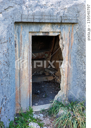 Ancient rock cut tomb entrance carved into a weathered stone cliff 139540797