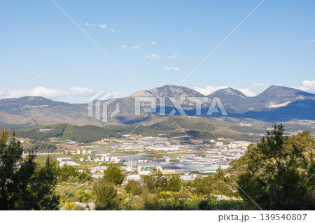 Greenhouse structures in a rural valley against a mountain landscape Greenhouse structures in a rural valley against a mountain landscape 139540807