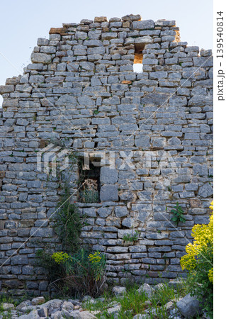 Ancient stone wall with weathered texture and yellow wildflowers Ancient stone wall with weathered texture and yellow wildflowers 139540814